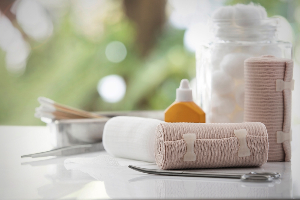 Bandage and first aid kit on white table, bokeh background.